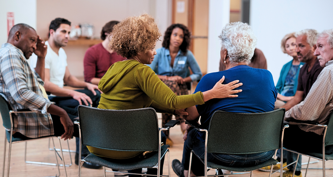 Group therapy setting, individuals sitting in a circle sharing stories and supporting each other