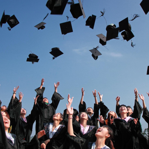 College students graduating tossing graduation caps into the air