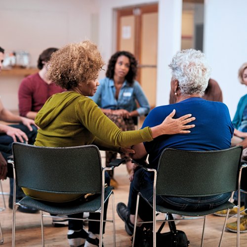 Group therapy setting, individuals sitting in a circle sharing stories and supporting each other